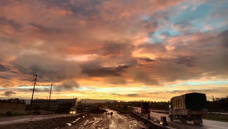 Mombasa Road outside Nairobi at sunrise after rain, with lorries heading out under a dramatic sky.